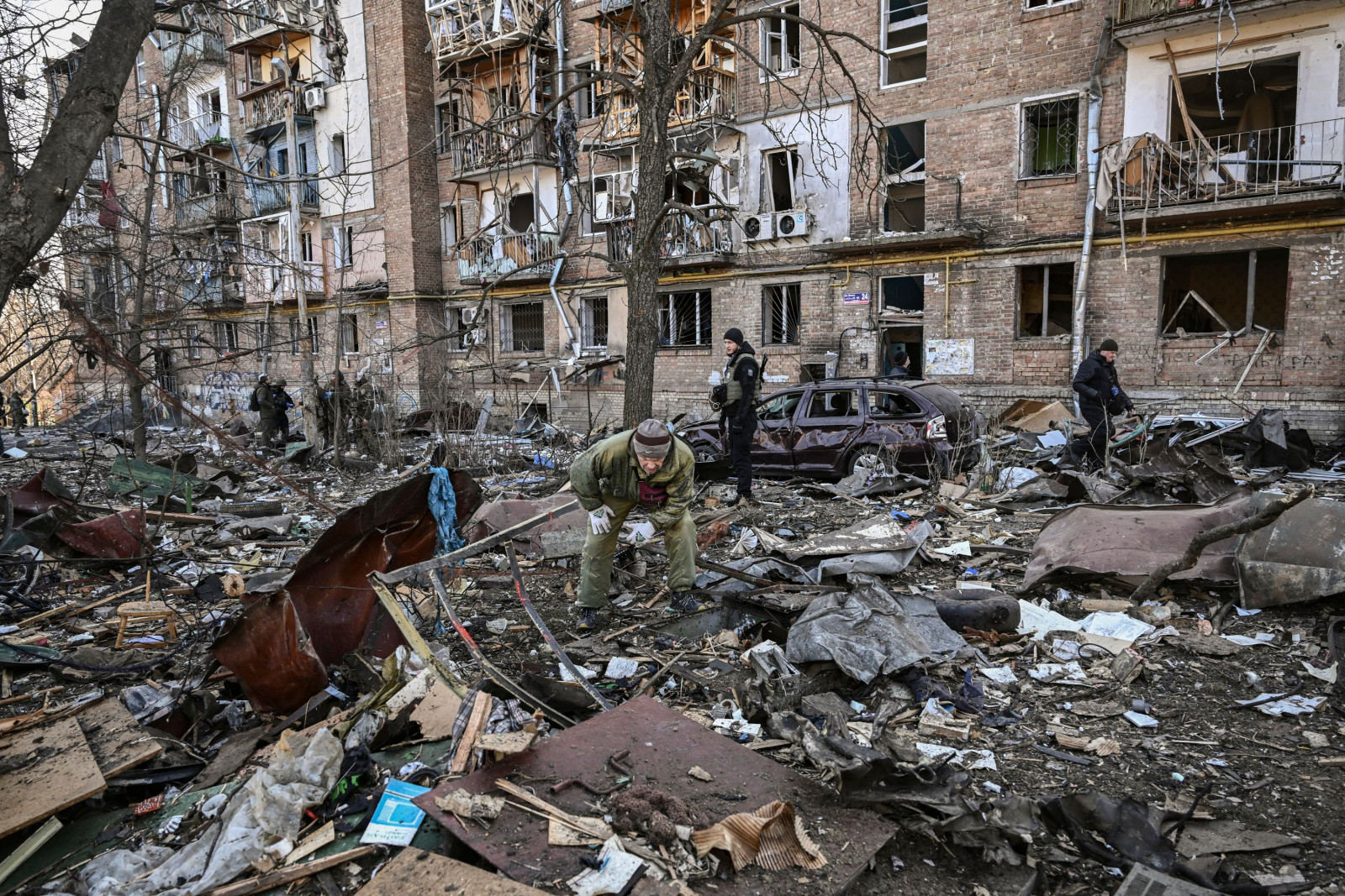 Украины цэргийн албан хаагчид 3-р сарын 18-нд Киев хотыг буудсаны дараа орон сууцны хороололд эвдэрсэн барилгын хажууд зогсож байна.